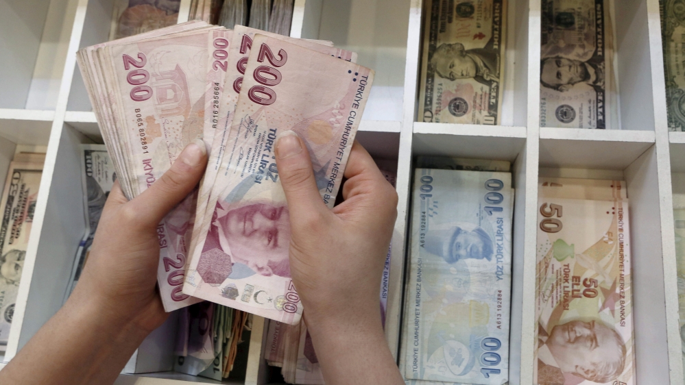A money changer counts Turkish lira bills at an currency exchange office in central Istanbul, Turkey