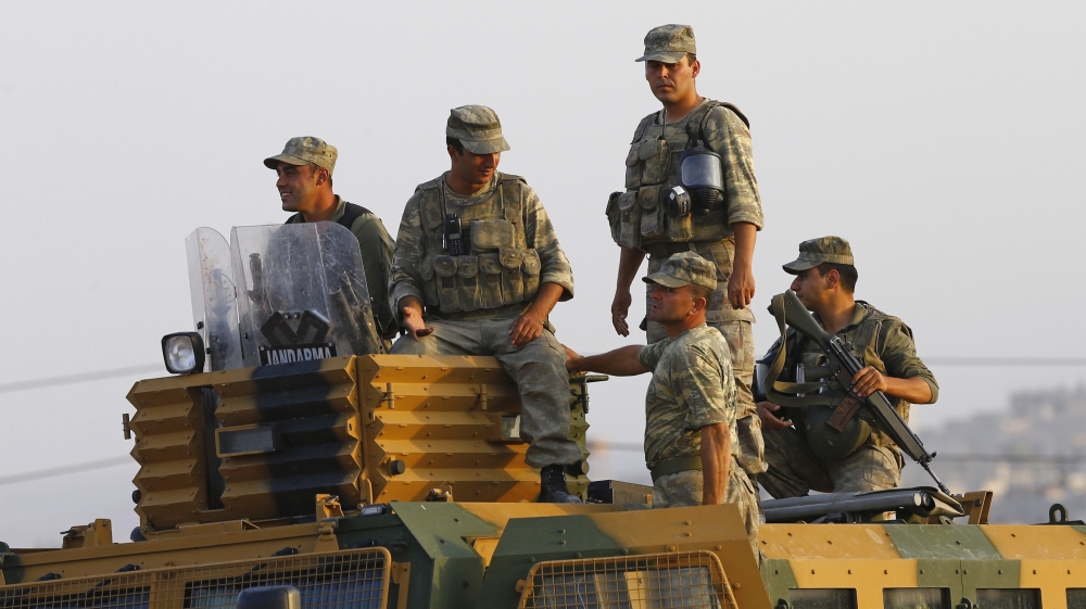 Turkish soldiers stand on top of an armoured vehicle near the Mursitpinar border crossing on the Turkish-Syrian border
