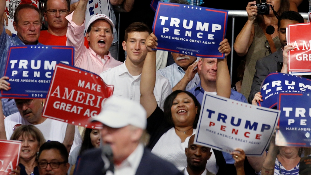 People cheer as Republican presidential nominee Donald Trump speaks on a stage during a campaign event in Dimondale