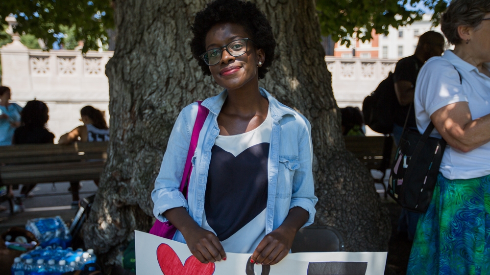 Barbara Okeny poses for a photograph as she waits for the Coalition's rally to begin  [Carolyn Bick/Al Jazeera]  