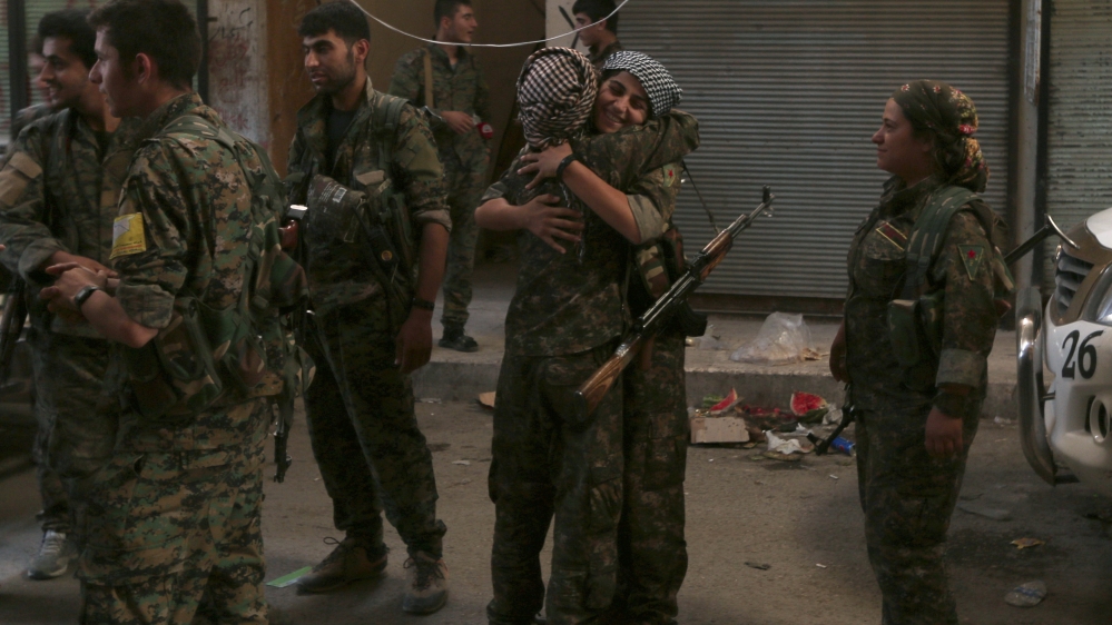 Syria Democratic Forces (SDF) female fighters embrace each other in the city of Manbij, in Aleppo Governorate