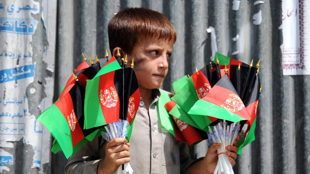 An Afghan boy sells the national flag on a roadside in Jalalabad, Afghanistan [EPA]