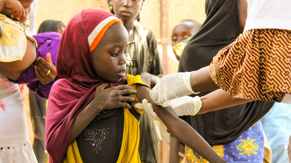 A Nigerian refugee girl receives healthcare from an aid worker of Doctors Without Borders [Lucas Desrtrijcker/Al Jazeera] 