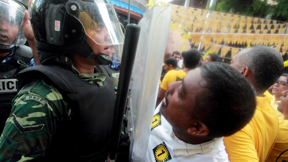 A supporter of Maldives presidential candidate Mohamed Nasheed shouts slogans in front of a police officer during a protest in Male, after the presidential run-off election was called off