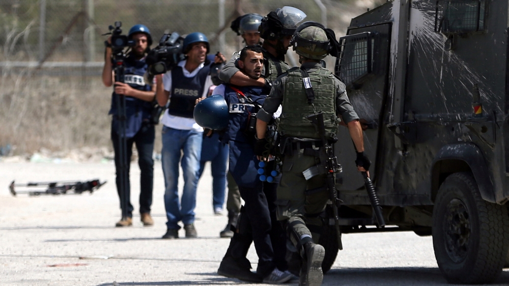 Israeli border policemen detain a Palestinian journalist during clashes with Palestinian protesters near Israel''s Ofer Prison near the West Bank city of Ramallah