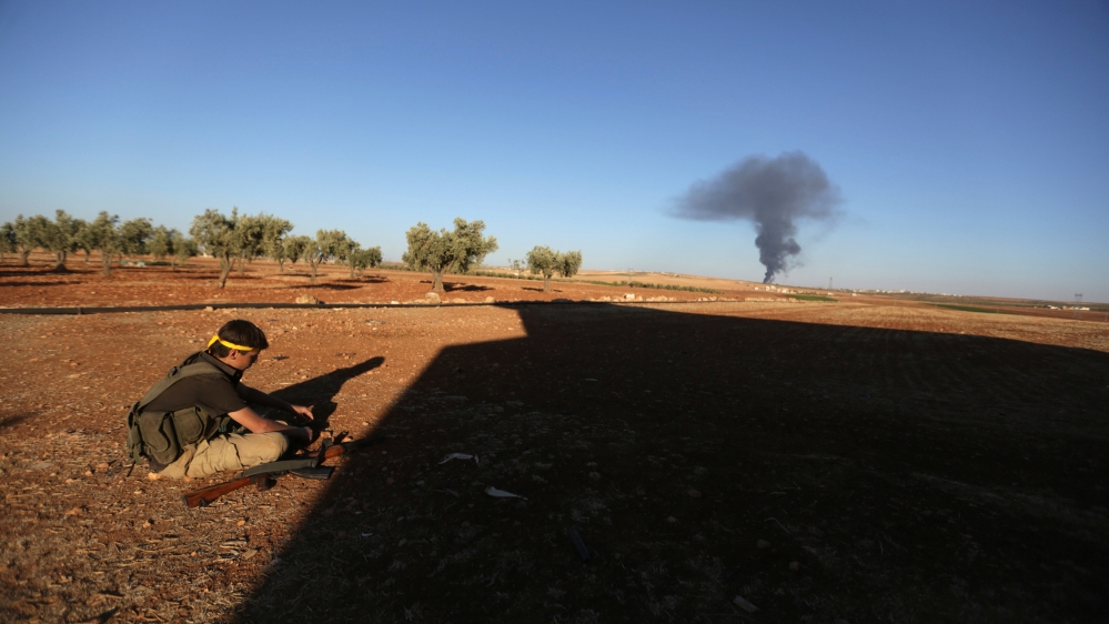 A rebel fighter sits near rising smoke from al-Bab city, northern Aleppo province