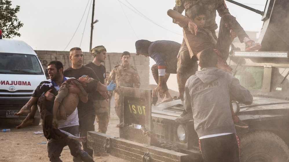 Mohammed, 12, and a 15-year-old neighbour are carried from an Iraqi army Humvee at an outdoor field clinic in Mosul's Samah district. The boys were hit in a mortar attack that shredded Mohammed's leg and killed Shafiq [John Beck/Al Jazeera]
