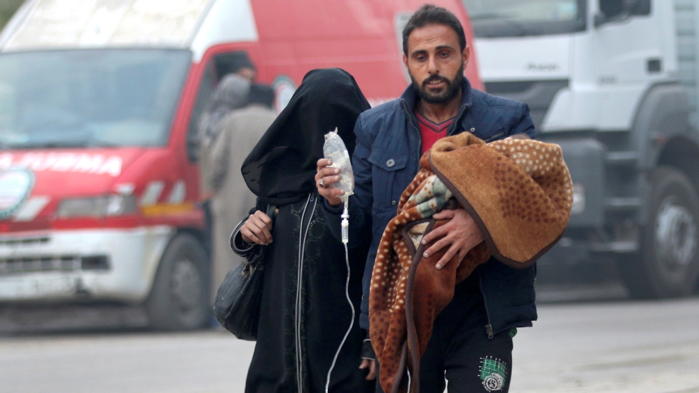 A man carries a child with an IV drip as he flees deeper into the remaining rebel-held areas of Aleppo