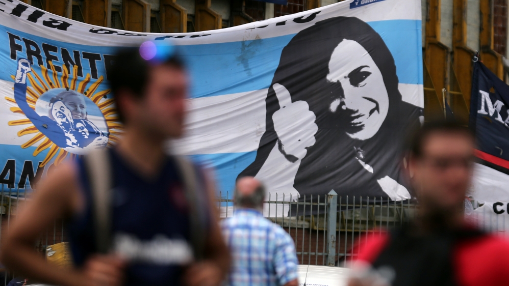 Supporters of former Argentine President Fernandez de Kirchner stand in front of a banner with her image as they wait for her to leave court in Buenos Aires
