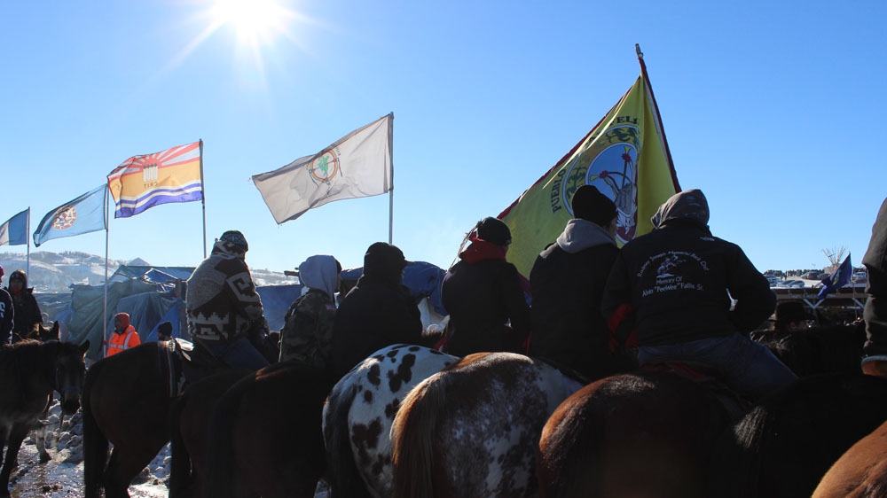 Young men sit on horseback following the 'victory' announcement, listening to speeches around the central fire [Adam Levinson/Al Jazeera] 