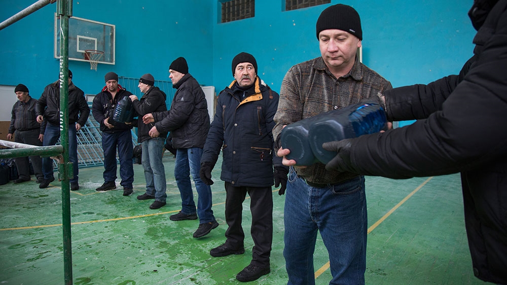 Bottled water is handed through a window and passed down a line of volunteers to be stacked and readied for distribution to people in Avdiivka. Water, electricity and heating were off or intermittent all last week. Though heat and power have returned in some places, water is still off [John Wendle/Al Jazeera] 
