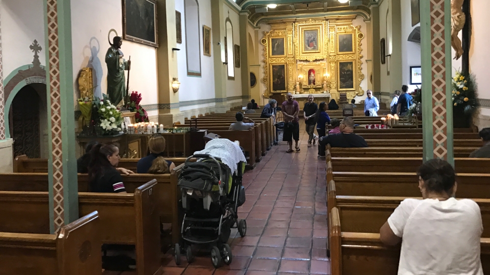 Congregants pray at Los Angeles' historical Our Lady Queen of Angels church. Download permissions [Massoud Hayoun/Al Jazeera]