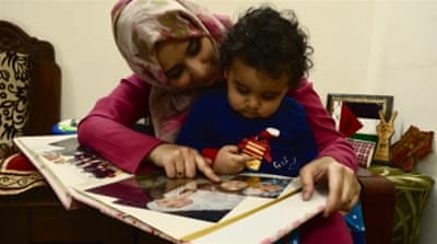 Maphaz shows baby Arafat pictures of her family in Gaza [Maya Prabhu/ Al Jazeera]