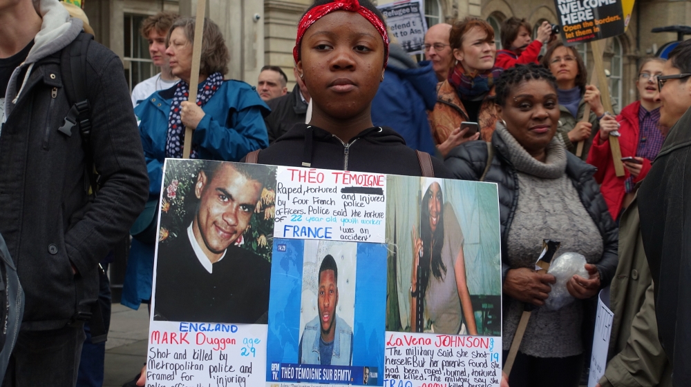 A protester carries a placard condemning police brutality [Shafik Mandhai/Al Jazeera]