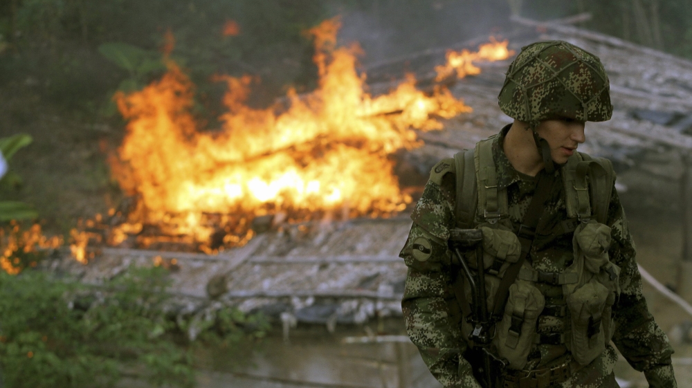 A soldier from the Seventh Division of the Colombian National Army looks on in front of a shack after members of the unit burn it down during an operation at a plantation in Yali