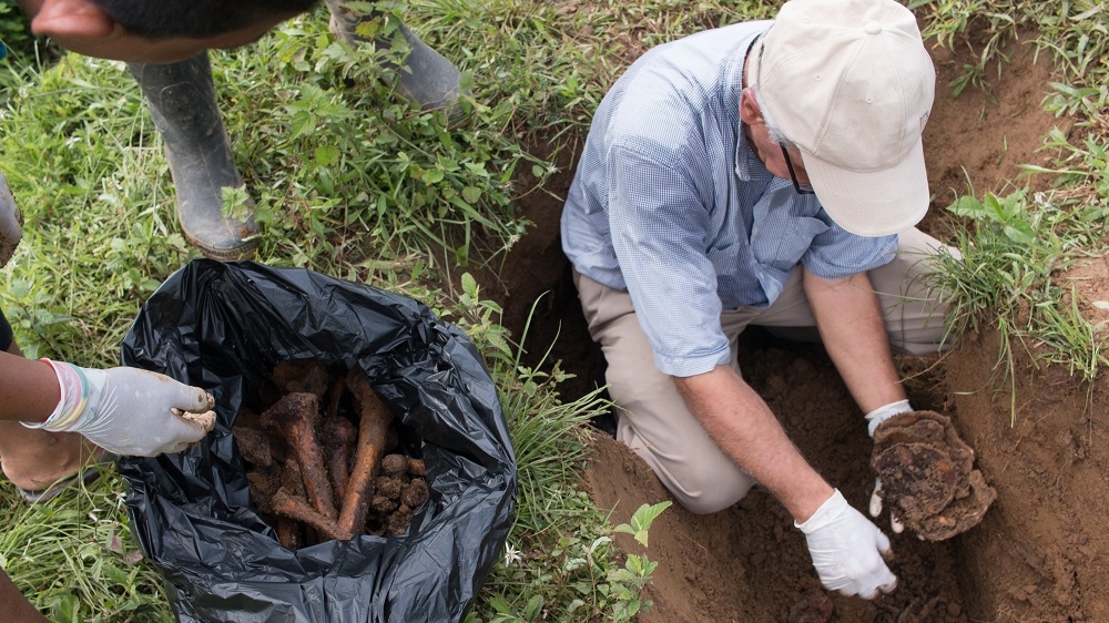 Father Javier Giraldo removes the remains of members of the community killed over the years to transfer them to above-ground graves [Joe Parkin Daniels/Al Jazeera]