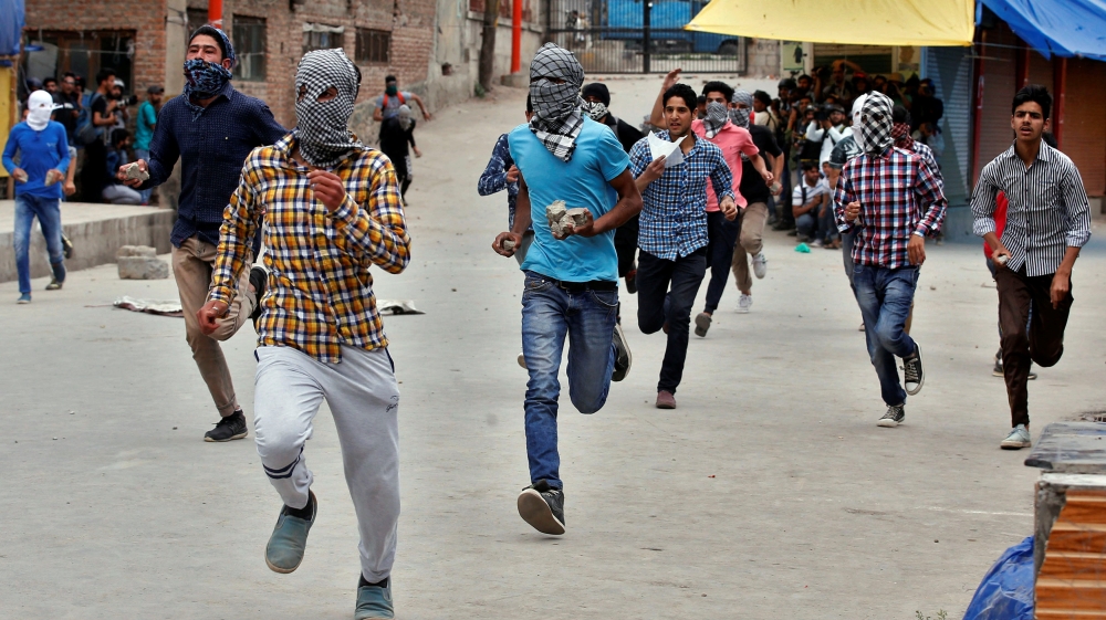 Protesters run as they prepare to hurl stones towards the Indian police during a protest after Friday prayers, in Srinagar