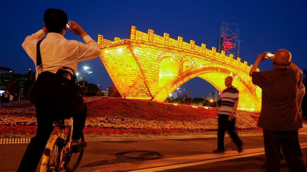 People take pictures of "Golden Bridge on Silk Road" installation by Shu Yong ahead of the Belt and Road Forum in Beijing
