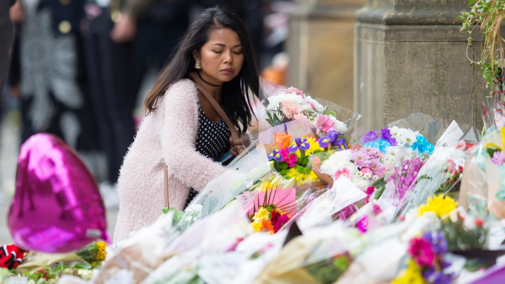 A woman places flowers on an impromptu memorial at Manchester Town Hall for the victims of an attack at Manchester Arena, Manchester