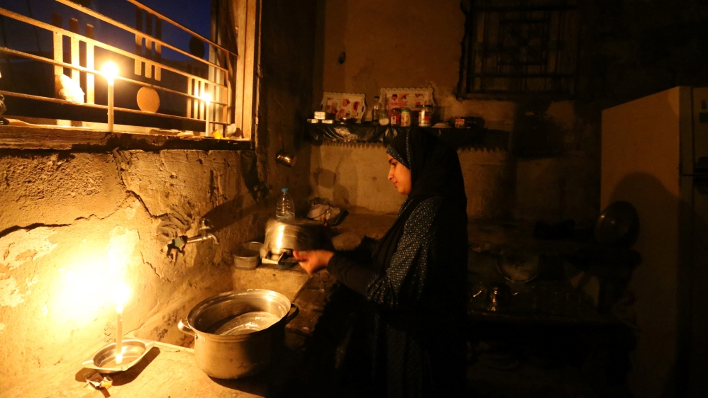 Palestinian girl cleans the kitchen of her house during power cut in the southern Gaza Strip