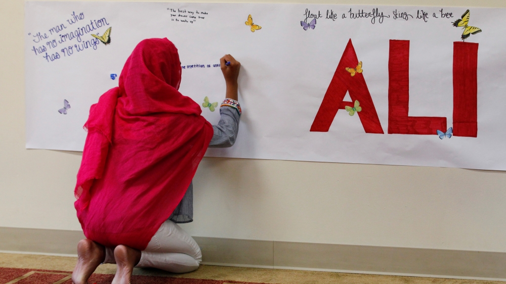 A member of the Louisville Islamic Center writes messages on a memorial banner as she pays her respect to Muhammad Ali, the former world heavyweight boxing champion after he died at the age of 74 on F