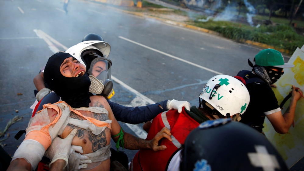 An injured opposition supporter is helped by volunteer members of a primary care response team during clashes with riot security forces at a rally against Venezuelan President Maduro