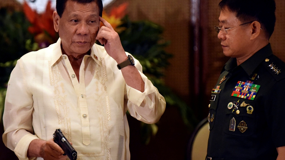 
President Rodrigo Duterte holds a 45 calibre pistol while standing with Eduardo Ano, a Chief of the Armed Forces [File: Dondi Tawatao/AFP]
