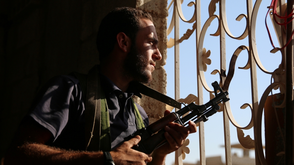 A Free Syrian Army fighter looks out through a window in rebel-held Al-Yadudah village, in Deraa Governorate, Syria