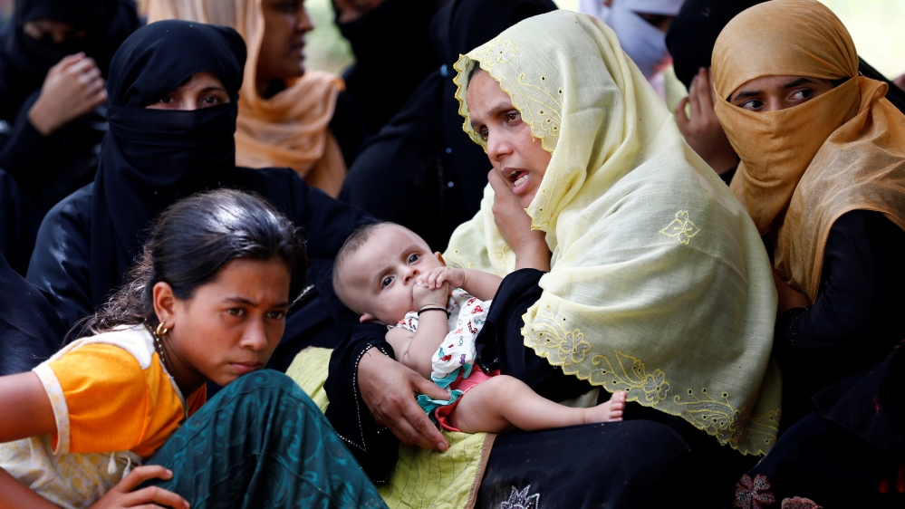 A Rohingya refugee woman with a child talks over phone as she takes shelter in No Man’s Land between Bangladesh-Myanmar border, in Cox’s Bazar
