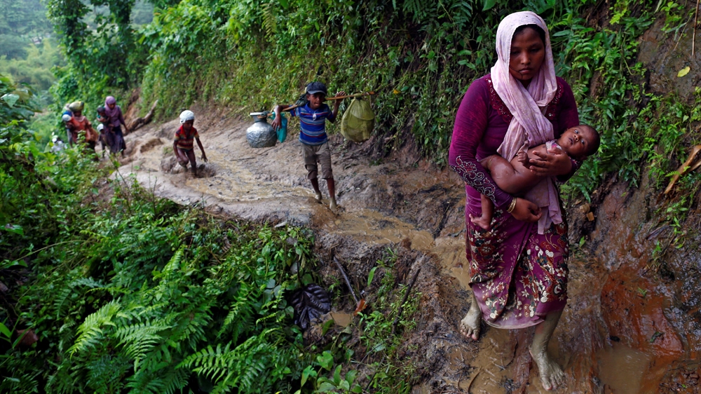 Rohingya refugees climb up a hill after crossing the Bangladesh-Myanmar border