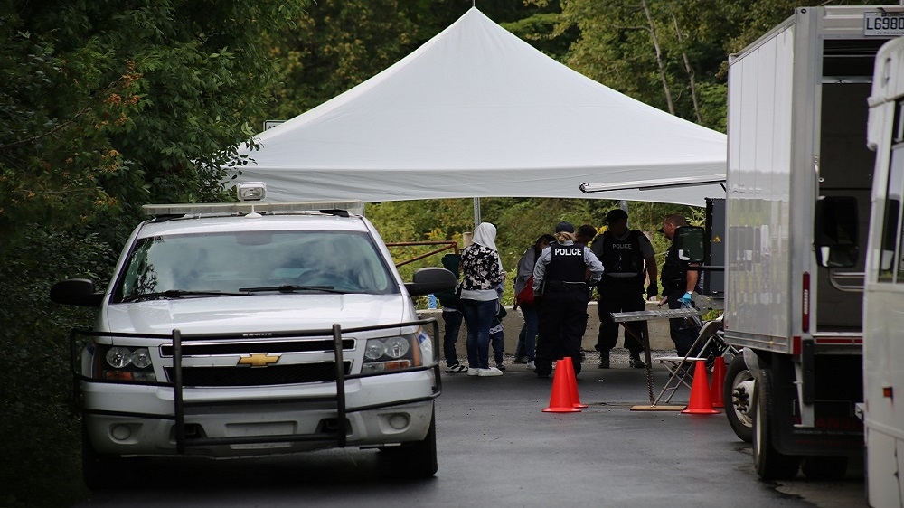 Asylum seekers are arrested and processed by police officers on the Canadian side of the Roxham Road border crossing [Blake Sifton/Al Jazeera]