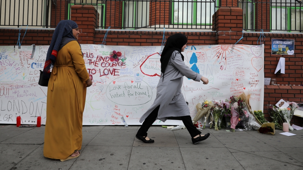 A woman walks past messages attached to a wall near the scene of an attack next to Finsbury Park Mosque, in north London