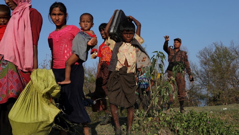 Rohingya refugees carry their belongings after arriving on an improvised raft to the banks of the Naf river in Teknaf