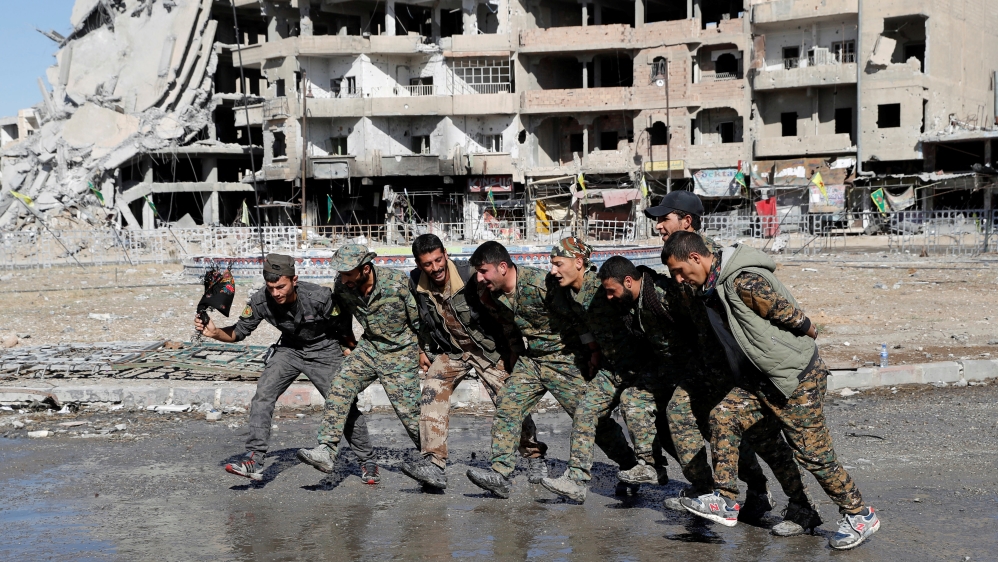 Syrian Democratic Forces fighters dance along street in Raqqa