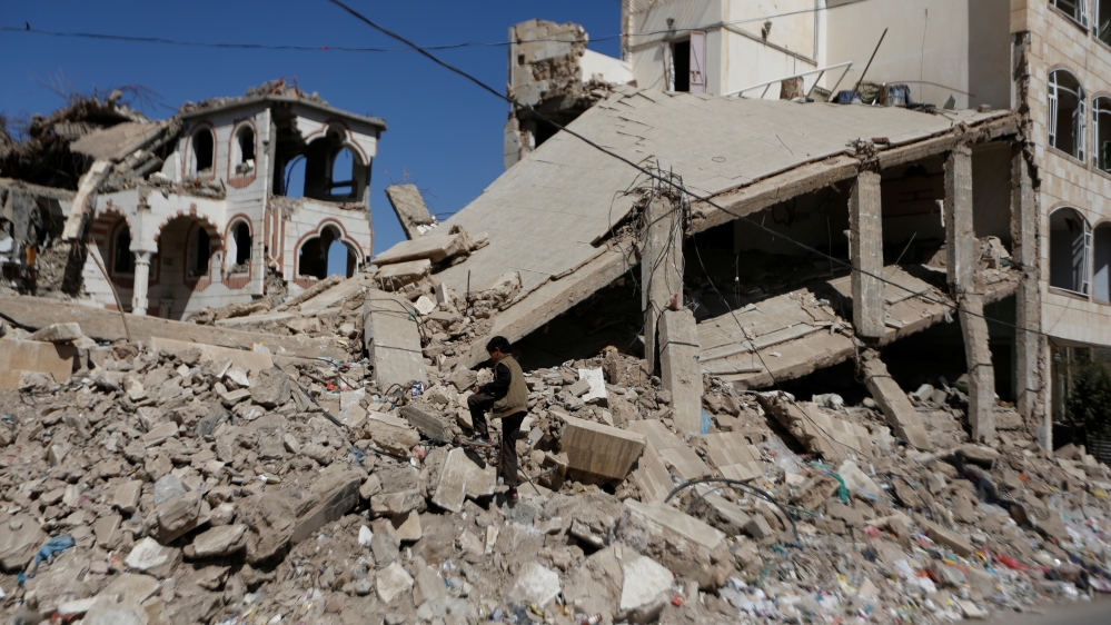 Boy walks on the wreckage of a building hit by air strikes two years ago in Sanaa