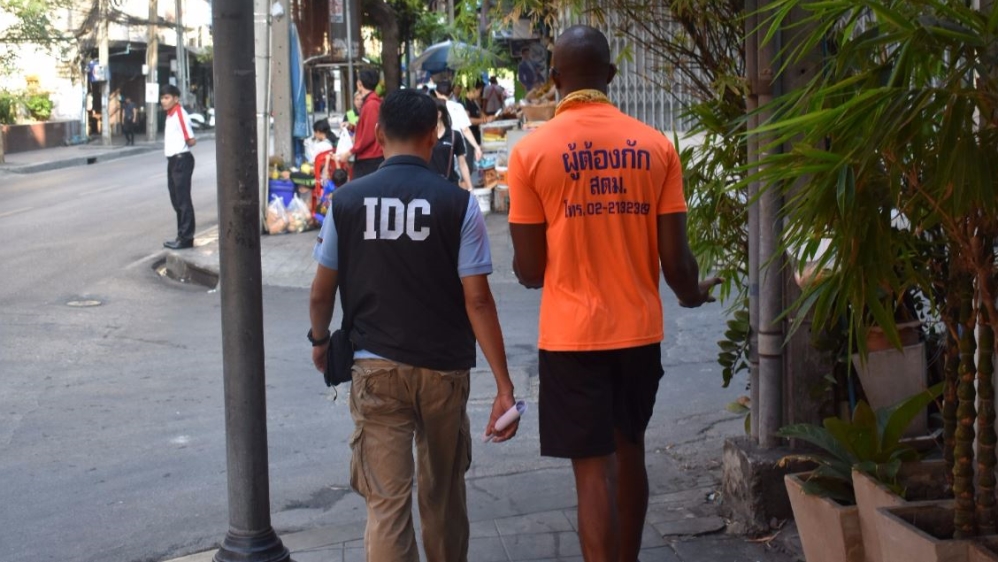  A detention centre guard escorts a detainee to the bank. Detainees are charged to use phones and other essential services inside the centres [Alastair G M/Al Jazeera] 