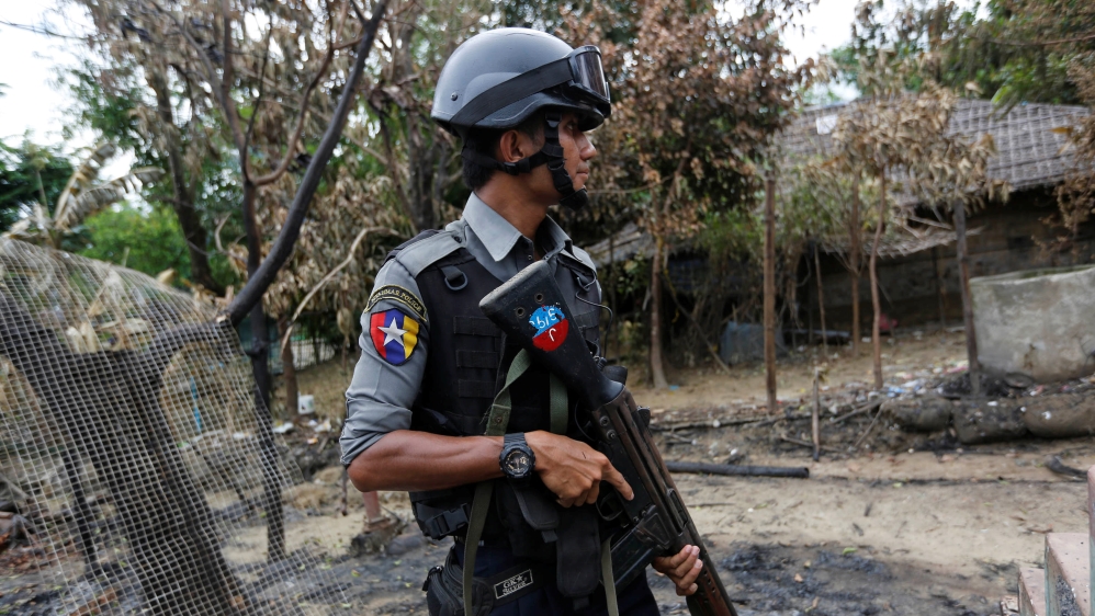 Police officer guards near a house which was burnt down during the last days of violence in Maungdaw