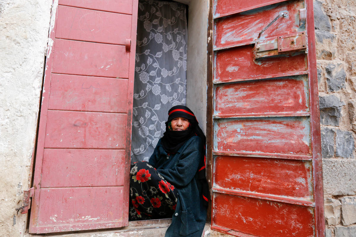Forced to flee her home in Sana’a governorate’s Bani Matar district after it was battered by intensified hostilities, 70 year old widow, Qafia, passes time at the entrance of a small house she rents i