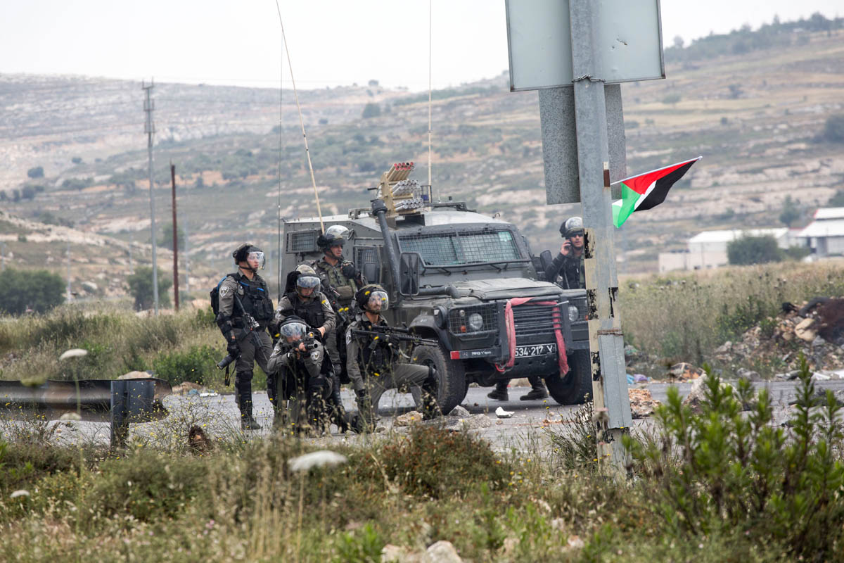 An Israeli soldier points his riffle towards the Palestinian protesters (unseen).