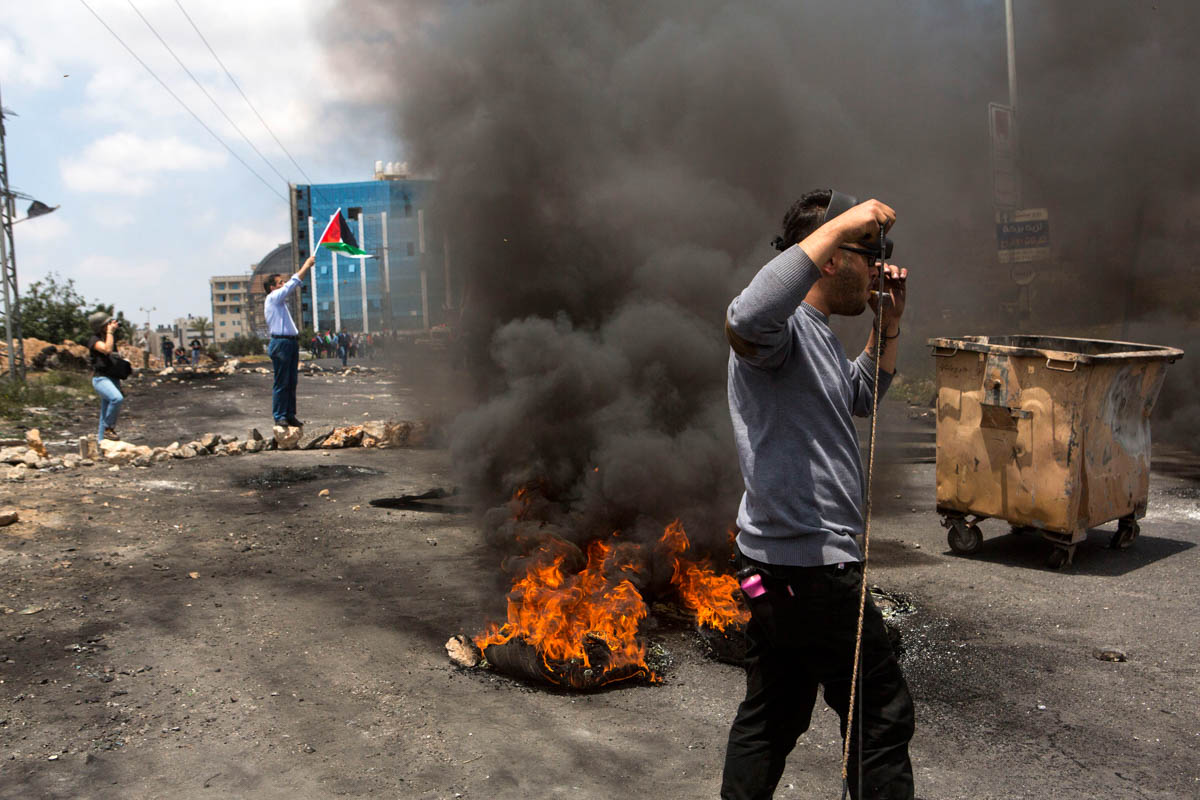 A Palestinian youth smokes during clashes for Nakba Day. The clashes lasted for hours. Due to the proximity with Ramallah, the area near Beit El settlement and compound is regularly the theater of cla