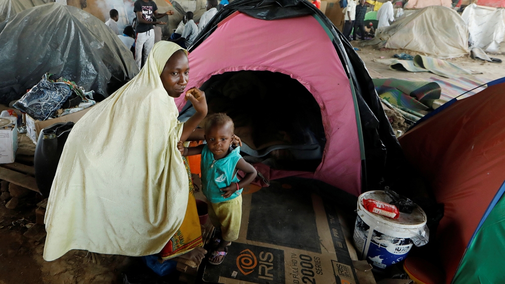 An African migrant sits with her son beside her tent at a makeshift camp on the outskirts of Algiers [Zohra Bensemra/Reuters]