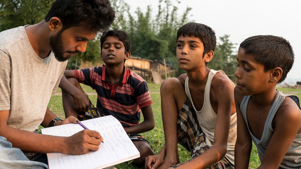Kazi Neel writes poetry in Miya dialect and also teaches children from the community [Al Jazeera]
