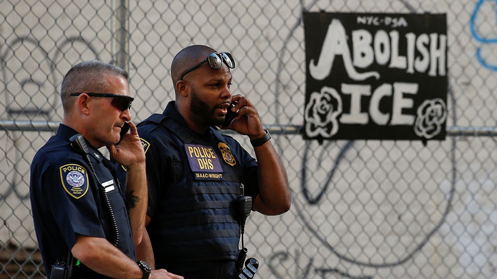 Department of Homeland Security officers watch members of Occupy ICE outside the ICE offices in New York City [Brendan McDermid/Reuters]