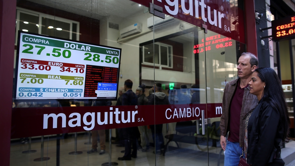 Pedestrians look at an electronic board showing currency exchange rates in Buenos Aires'' financial district, Argentina, June 28, 2018.