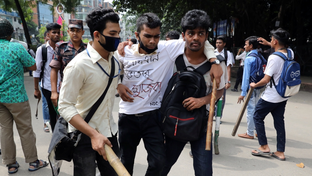 An injured student is helped during clashes with unidentified miscreants while they are protesting over recent traffic accidents that killed a boy and a girl, in Dhaka