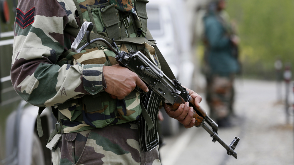 An Indian army soldier stands guard during a gun battle in Khudwani village, south of Srinagar, in April [Mukhtar Khan/The Associated Press]