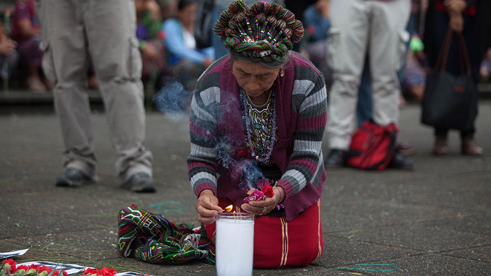 Ana de Leon lights a candle outside of the Guatemalan Supreme Court during the ceremony commemorating the victims of the internal armed conflict [Jeff Abbott/Al Jazeera]