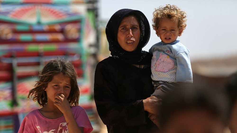 A woman who fled her village in Syria''s Idlib province carries a child at a camp in Kafr Lusin near the border with Turkey in the northern part of the province on September 9, 2018. Regime and Russian