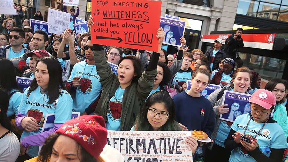Sarah Chung, a junior at Harvard University, holding an orange sign at centre, participates in a 'defend diversity' pro-affirmative-action rally in Harvard Square on Tuesday [Pat Greenhouse/The Boston Globe/Getty Images] 