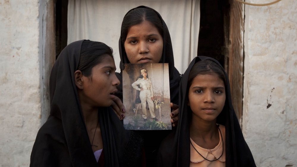 The daughters of Pakistani Christian woman Asia Bibi pose with an image of their mother while standing outside their residence in Sheikhupura located in Pakistan''s Punjab Province November 13, 2010.